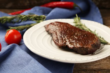 Kompozisyon plaka, domates ve biberiye dal ahşap zemin üzerine kavrulmuş lezzetli etli