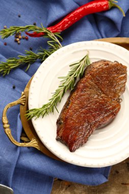 Kompozisyon plaka, domates ve biberiye dal ahşap zemin üzerine kavrulmuş lezzetli etli