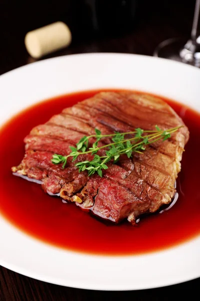 Gegrilde steak in wijnsaus op plaat op tafel close-up — Stockfoto