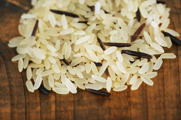 Grãos de arroz sobre fundo de madeira — Fotografia de Stock