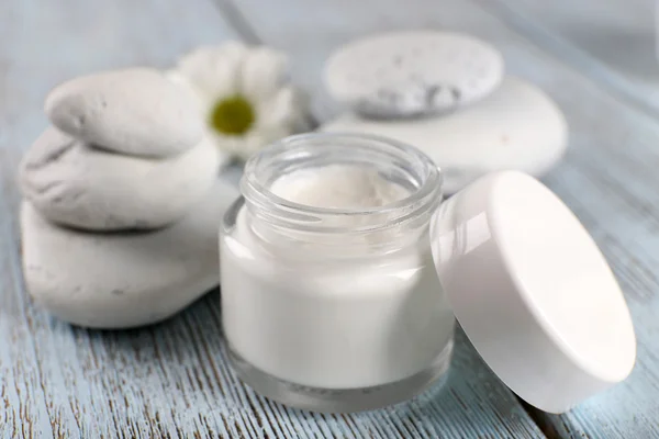 Cosmetic cream with spa stones and chamomile on wooden background — Stock Photo, Image