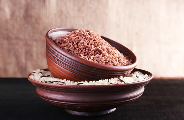 Granos de arroz en cuencos sobre la mesa sobre fondo de saco —  Fotos de Stock