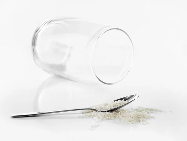 Remnants of rice in spoon with glass jar isolated on white — Stock Photo, Image
