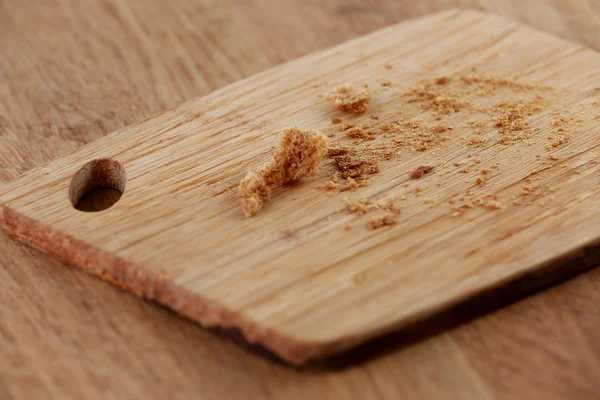 Bread crumbs on cutting board on wooden background — Stock Photo, Image