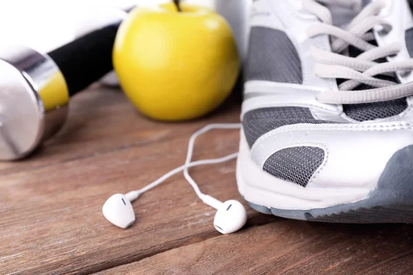 Sapatos esportivos com haltere e fones de ouvido em fundo de madeira — Fotografia de Stock