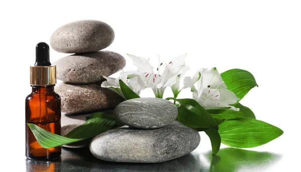 Pedras de spa com óleos aromáticos e flores isoladas em branco — Fotografia de Stock