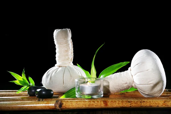 Hermosa composición con bolsas de masaje y vela en la mesa sobre fondo oscuro —  Fotos de Stock