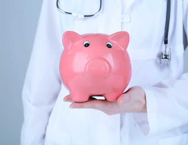 Doctor with pink piggy bank — Stock Photo, Image