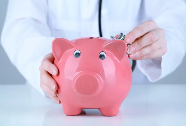 Doctor with pink piggy bank — Stock Photo, Image