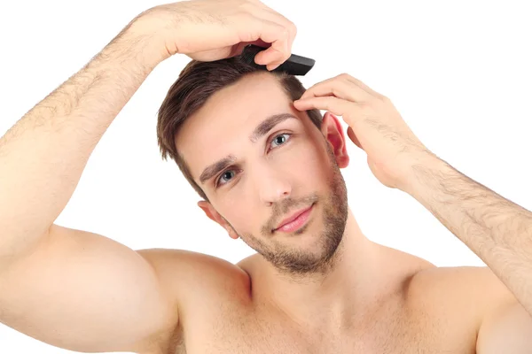 Schöner junger Mann kämmt seine Haare isoliert auf weiß — Stockfoto