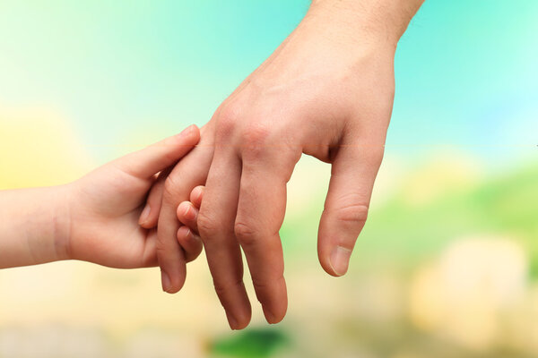 Child and father hands on bright background