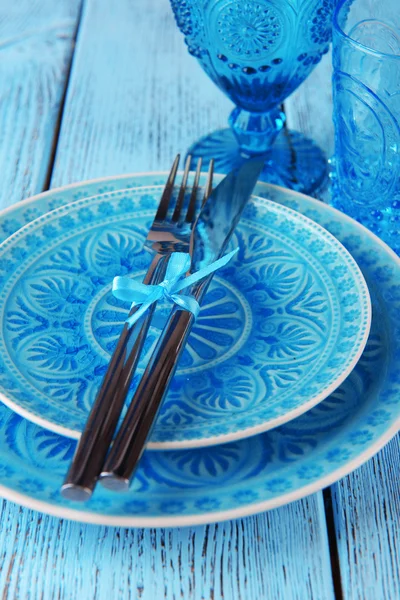 Pusty kolorowy talerz, szklanki i srebrne naczynia na drewnianym stole — Zdjęcie stockowe