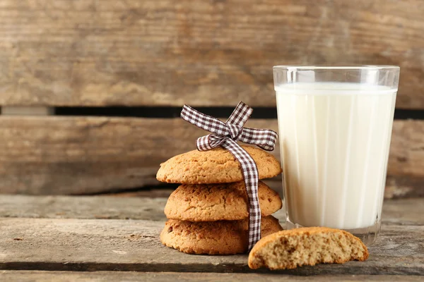 Sabrosas galletas y vaso de leche sobre fondo rústico de madera — Foto de Stock