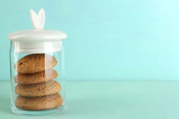 Tasty cookies in glass jar on color wooden background — Stock Photo, Image