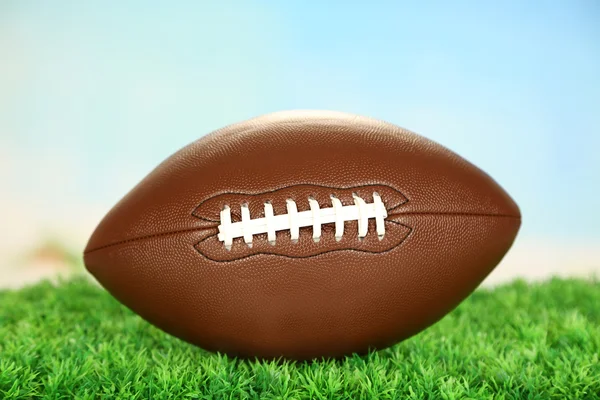 American football on field on green grass, on blue sky background