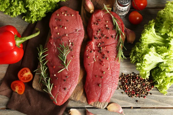 Raw beef steak with spices and greens on table close up — Stock Photo, Image