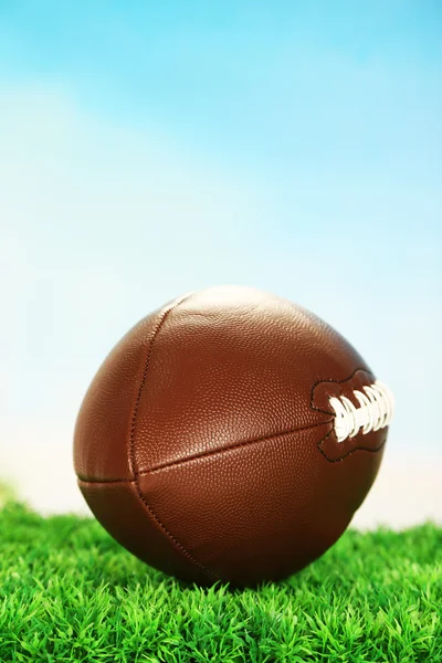 Fútbol americano en el campo sobre hierba verde, sobre fondo azul cielo — Foto de Stock