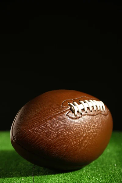 American football on green grass, on black background — Stock Photo, Image