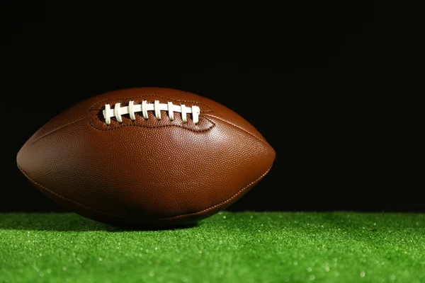 Football americano su erba verde, su sfondo nero — Foto Stock