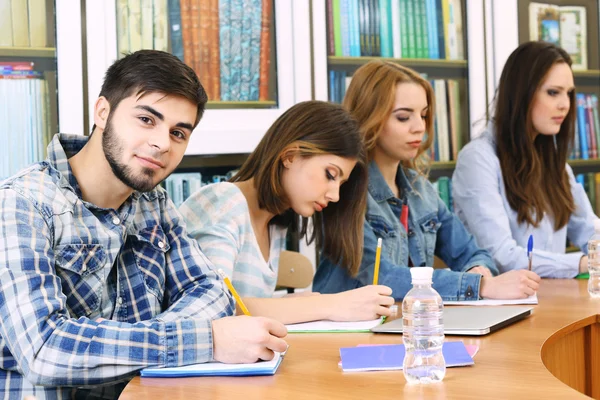 Skupina studentů sedících u stolu v knihovně — Stock fotografie