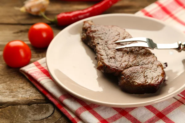 Composition with tasty roasted meat on plate, vegetables on wooden background — Stock Photo, Image