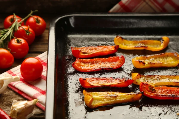 Composition with roasted sliced pepper on pan, tomatoes and rosemary sprigs on wooden background — Stock Photo, Image