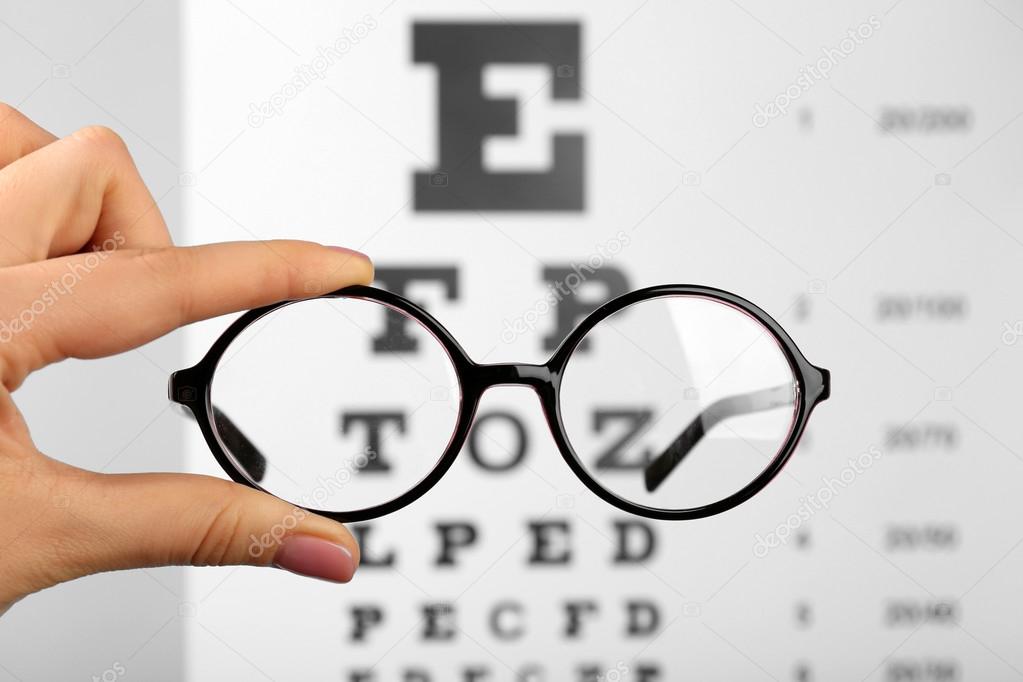 Glasses in hands on eye chart
