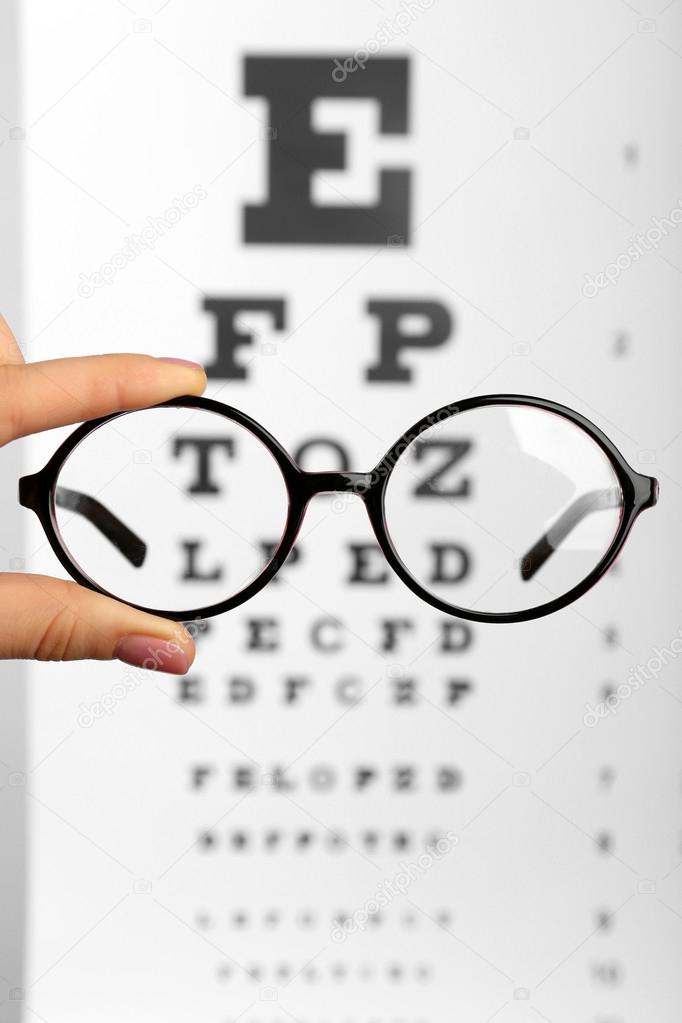 Glasses in hands on eye chart