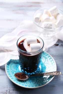 Sıcak çikolata şekerleme cam, renkli ahşap arka plan üzerinde