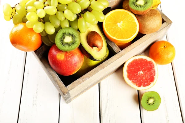 Surtido de frutas en caja sobre mesa de madera — Foto de Stock