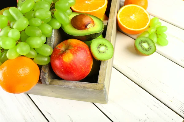 Assortment of fruits in box on wooden table — Stock Photo, Image