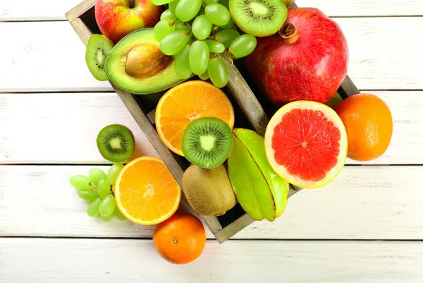 Assortment of fruits in box on wooden table