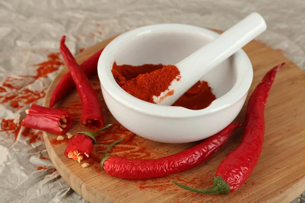 Ground red pepper in mortar with chili pepper on table close up — Stock Photo, Image