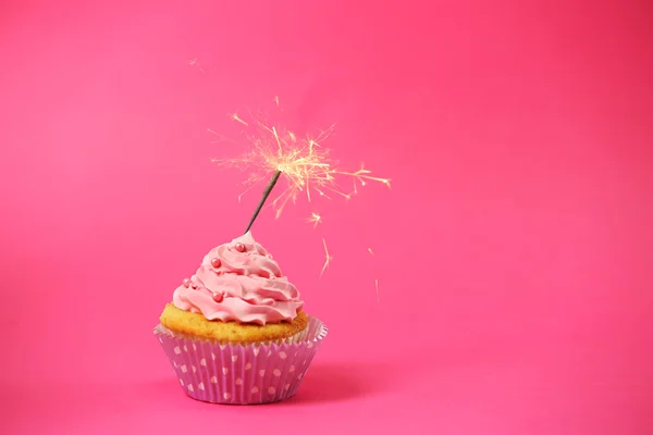 Cupcake with sparkler on pink background — Stock Photo, Image