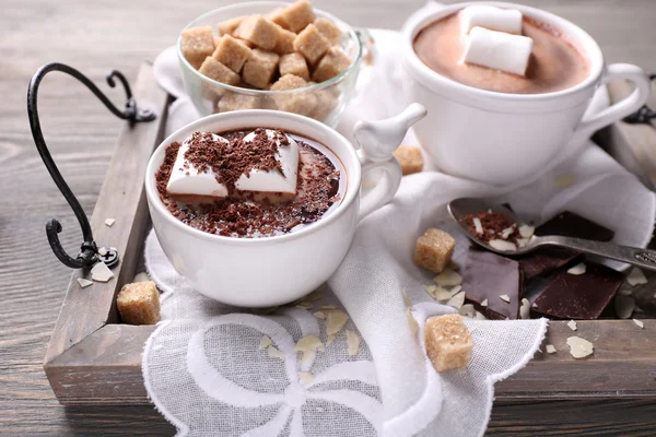 Cioccolata calda con marshmallow in tazza, su vassoio, su sfondo di legno a colori — Foto Stock