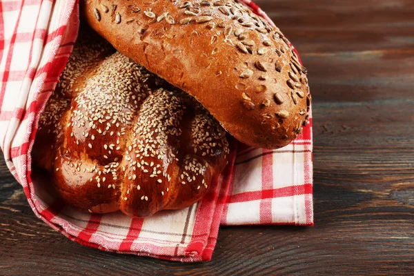 Pães frescos com pão com guardanapo na mesa de madeira fechar — Fotografia de Stock