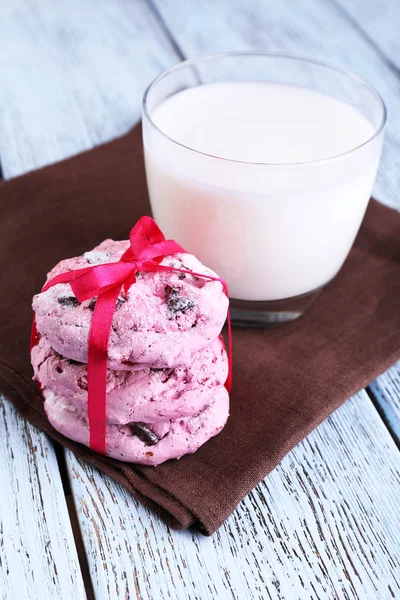 Розовое печенье и стакан молока на столе крупным планом — стоковое фото
