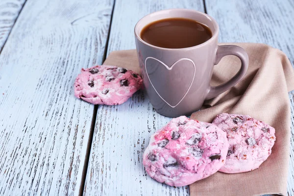 Розовое печенье и чашка кофе на столе крупным планом — стоковое фото