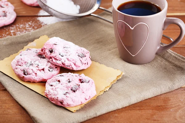 Pink cookies and cup of coffee on wooden table — Stock Photo, Image