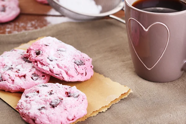 Pink cookies and cup of coffee on wooden table — Stock Photo, Image