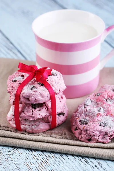 Różowy cookies i kubek z mleka na stół szczegół — Zdjęcie stockowe