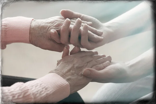 Old and young holding hands on light background, closeup — Stock Photo, Image