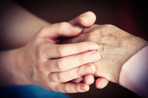 Old and young holding hands on light background, closeup — Stock Photo, Image