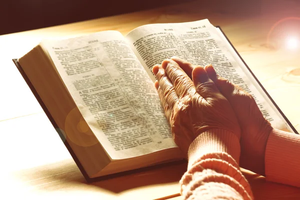 Hands of old woman with Bible on table, close-up — Stock Photo, Image