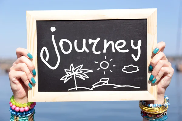 Journey concept. Blank chalkboard in female hands on beach background — Stock Photo, Image