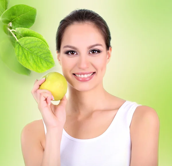 Beautiful young woman with green apple on light green background — Stock Photo, Image