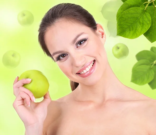 Hermosa joven con manzana verde sobre fondo natural — Foto de Stock