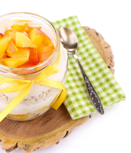 Petit déjeuner sain - yaourt aux pêches fraîches et muesli servi dans un bocal en verre sur un plateau en bois, isolé sur du blanc — Photo