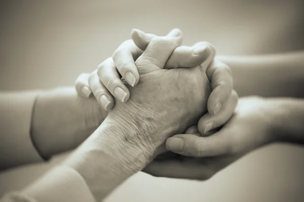 Old and young holding hands on light background, closeup — Stock Photo, Image