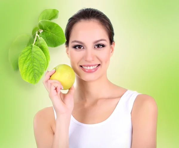 Όμορφη νεαρή γυναίκα με το πράσινο μήλο σε ανοιχτό πράσινο φόντο — Φωτογραφία Αρχείου